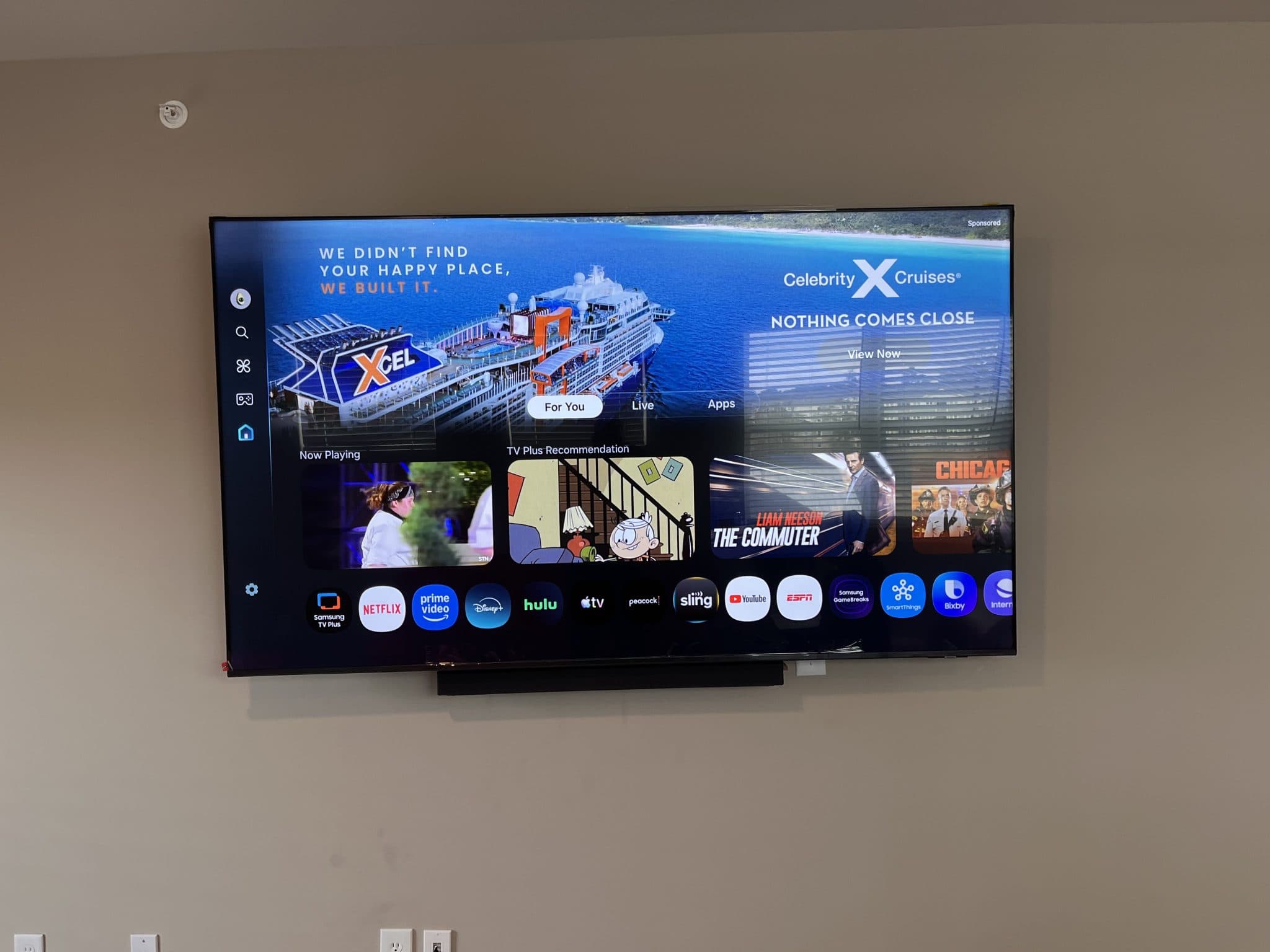 Samsung TV wall-mounted with a sound bar underneath in a living room