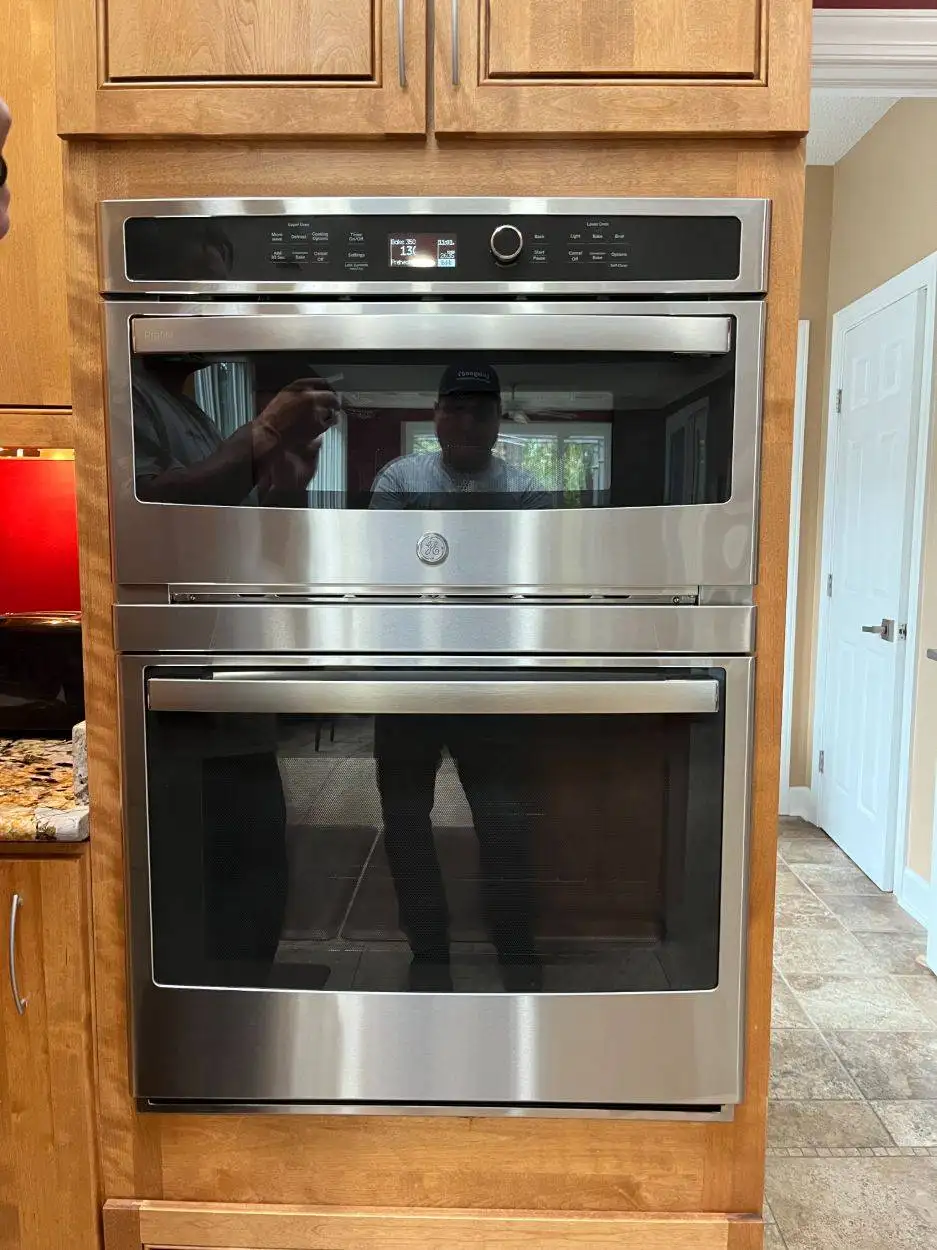Installation of a stainless steel oven and microwave set within wood-finish kitchen cabinetry